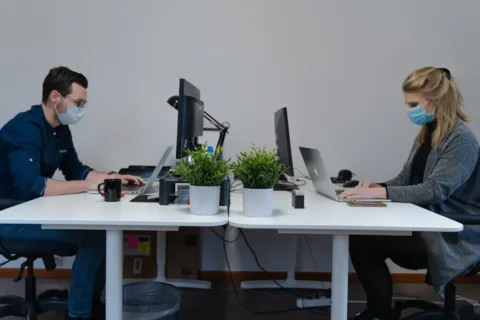 Pekerja kantor menerapkan tips menjaga kesehatan di tempat kerja dengan peregangan ringan