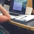 Mahasiswa sedang menggunakan laptop untuk mengerjakan tugas kuliah di lingkungan kampus