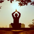 Seseorang sedang melakukan meditasi santai di alam untuk menerapkan cara menjaga pikiran tetap tenang