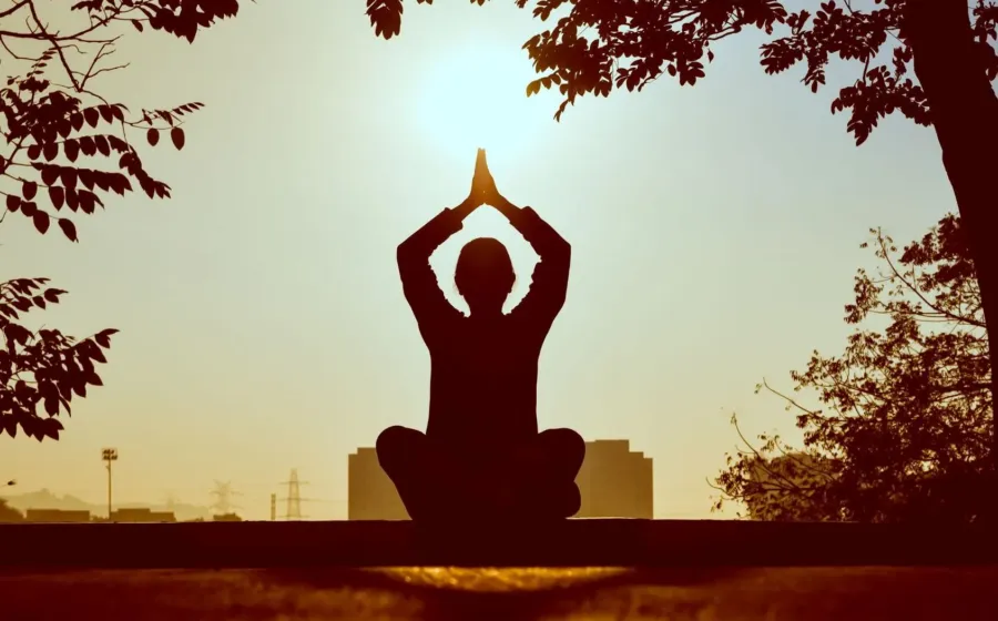 Seseorang sedang melakukan meditasi santai di alam untuk menerapkan cara menjaga pikiran tetap tenang