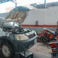 Mekanik sedang merawat kendaraan harian dan mengecek kondisi mesin mobil di bengkel