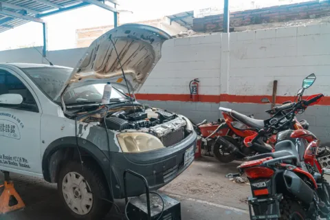 Mekanik sedang merawat kendaraan harian dan mengecek kondisi mesin mobil di bengkel