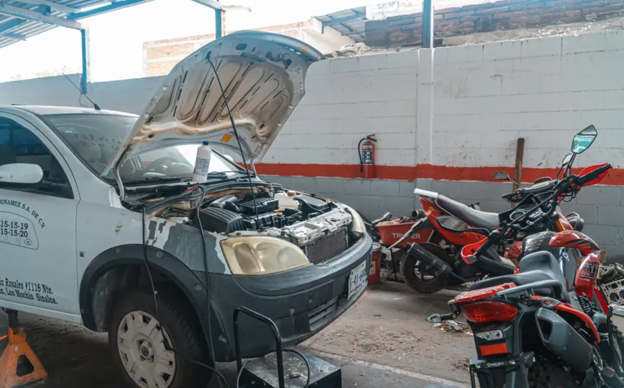 Mekanik sedang merawat kendaraan harian dan mengecek kondisi mesin mobil di bengkel