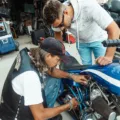 Seseorang sedang menerapkan tips merawat motor di rumah pada bagian mesin