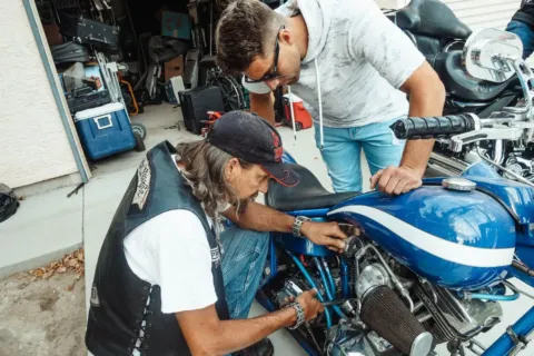 Seseorang sedang menerapkan tips merawat motor di rumah pada bagian mesin