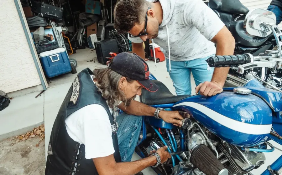 Seseorang sedang menerapkan tips merawat motor di rumah pada bagian mesin