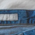 Seseorang sedang memilih celana jeans yang pas di toko pakaian