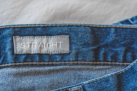 Seseorang sedang memilih celana jeans yang pas di toko pakaian