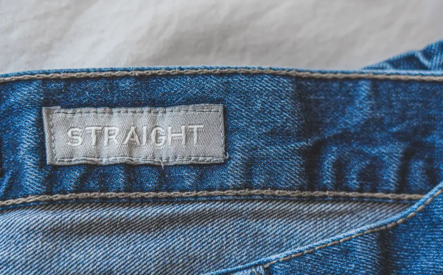 Seseorang sedang memilih celana jeans yang pas di toko pakaian
