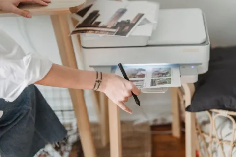 Seseorang sedang mengambil hasil cetakan kertas dari printer untuk rumah di atas meja kerja