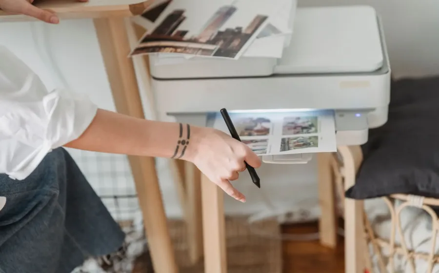 Seseorang sedang mengambil hasil cetakan kertas dari printer untuk rumah di atas meja kerja