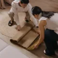 Karpet motif minimalis di lantai ruang tamu dengan sofa dan meja kayu, contoh tips memilih karpet rumah