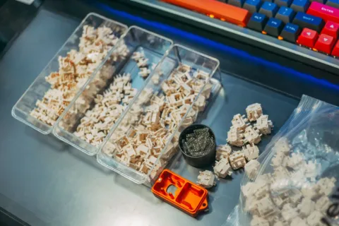 Seseorang sedang menguji switch keyboard mekanikal di atas meja kerja yang rapi