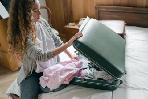 Pakaian traveling yang digulung rapi di dalam koper jinjing untuk menghemat ruang